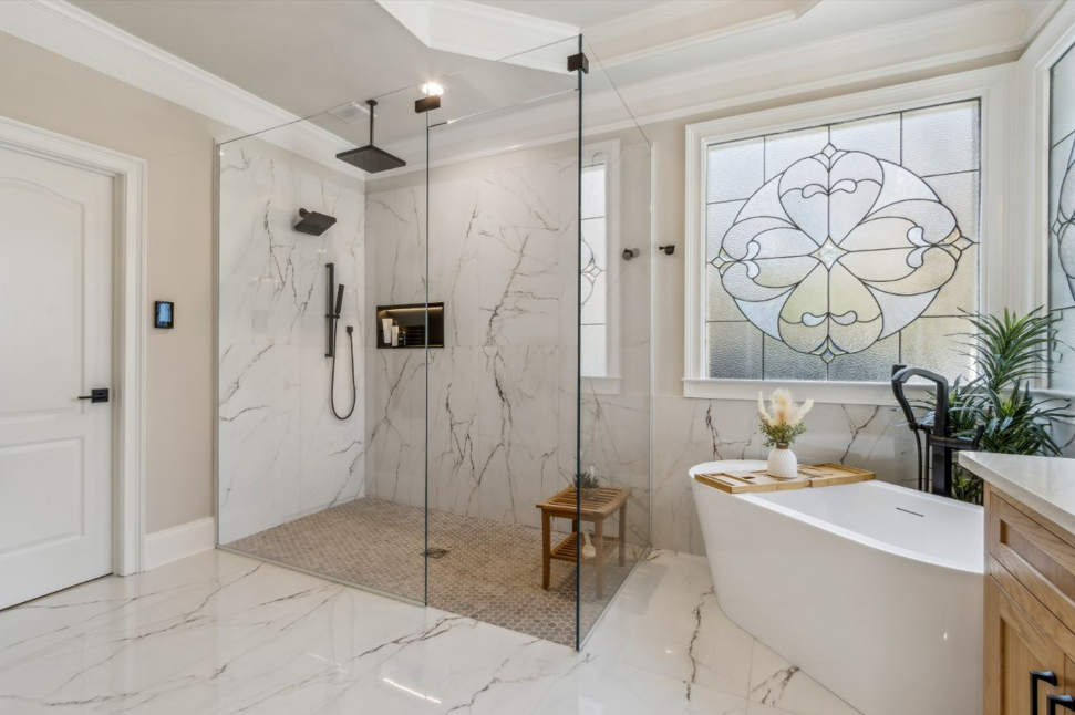 This is a glamorous low iron master shower with a transom above the entryway to provide additional structural support for the panels on each side. It almost disappears in the space!